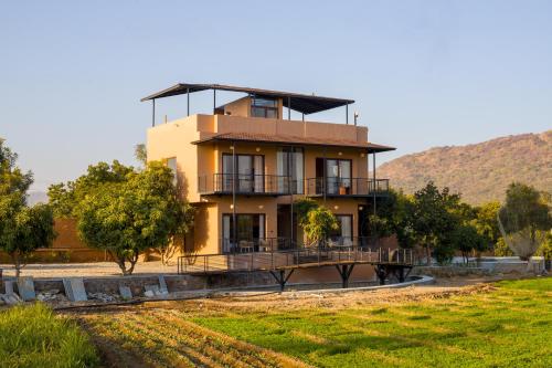 a large yellow house with a balcony and trees at ELIVAAS Cows & Cuddles 4 BHK with Pvt Pool and Garden in Debāri