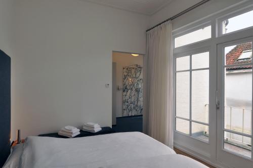 a white bedroom with a bed and a window at Boetiek Hotel Kampen in Kampen