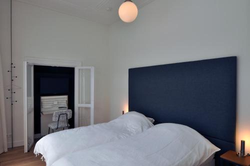 a bedroom with a large bed with a blue headboard at Boetiek Hotel Kampen in Kampen