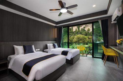 two beds in a hotel room with a large window at Aspira Escape Ao Nang Krabi in Ao Nang Beach
