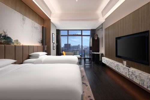 a hotel room with three beds and a flat screen tv at Sofitel Hangzhou Yingguan-Olympic Center Hotel in Hangzhou