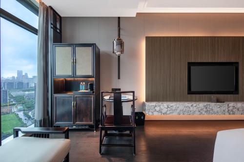 a living room with a tv and a couch at Sofitel Hangzhou Yingguan-Olympic Center Hotel in Hangzhou