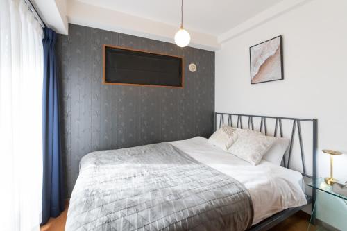 a bedroom with a bed and a tv on a wall at Impulse Imazato in Osaka