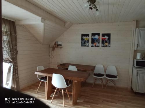a dining room with a wooden table and white chairs at Nota Bene Mykulychyn in Mykulychyn