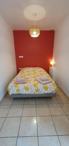 une chambre avec un lit et un mur rouge dans l'établissement Appartement 58m2 10min de la gare à pied, à Quimper