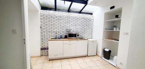 une cuisine avec des placards blancs et un mur en briques dans l'établissement Appartement 58m2 10min de la gare à pied, à Quimper