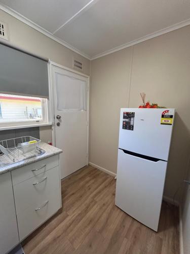 a kitchen with a white refrigerator in a room at #3 Waddell Studio Apartment in Canowindra