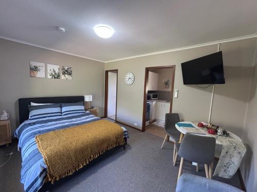 a bedroom with a bed and a table and a television at #2 Waddell Studio Apartment in Canowindra