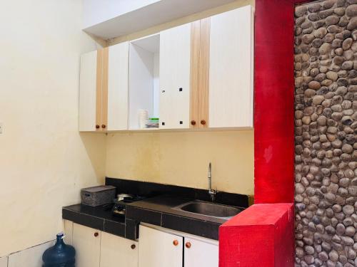 a kitchen with a sink and a red wall at Mulia Homestay Syariah Pasuruan in Randusari