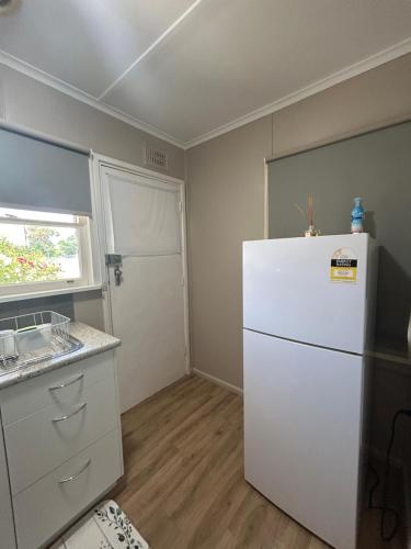 a kitchen with a white refrigerator and a window at #1 Waddell Studio Apartment in Canowindra