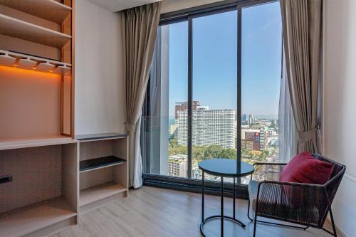a room with a table and chair and a large window at Edge Central Pattaya Sea view High Floor 23,26 in Pattaya