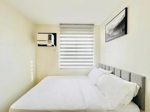 a bedroom with a white bed and a window at One Spatial Iloilo in Iloilo City