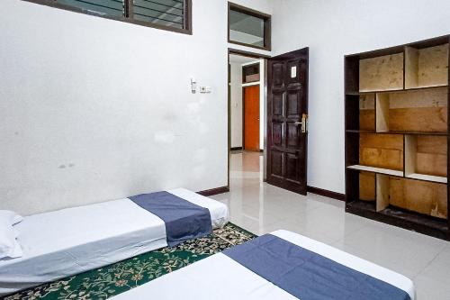 a bedroom with two beds and a door in it at RedDoorz at RRR Guesthouse Mataram in Tjakranegara