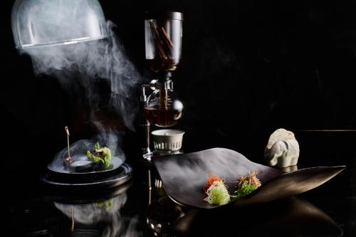 two dishes of food on a table with smoke at Siam Kempinski Hotel Bangkok in Bangkok