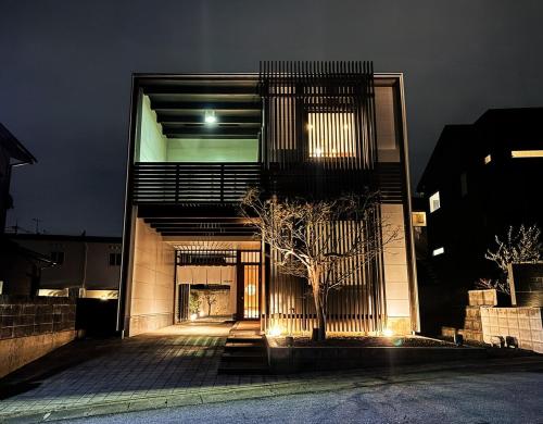 a building with a tree in front of it at night at Casa Villa 連歌屋 Wooden detached house in Dazaifu in Dazaifu