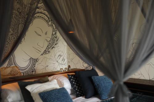a room with a bed with a painting on the wall at Akohara Buahan Village Retreat in Payangan