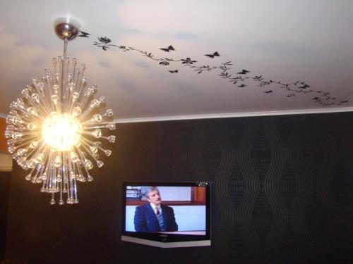 a chandelier and birds on a ceiling with a tv at Lux Apartment in Lisbon