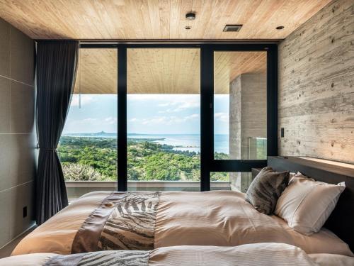 a bedroom with a large window and a large bed at Iluvio Resort Motobu in Motobu