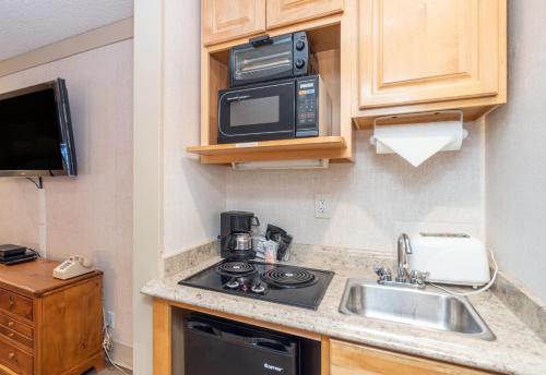 a small kitchen with a sink and a microwave at Mountainside Inn 417 by Alpine Lodging Telluride in Telluride