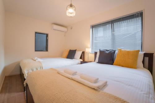 two beds in a room with a window at 旅タイム 住吉朱雀 in Osaka