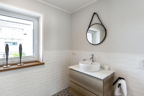 une salle de bains blanche avec un lavabo et un miroir dans l'établissement Deichlodge-4, à Büsumer Deichhausen