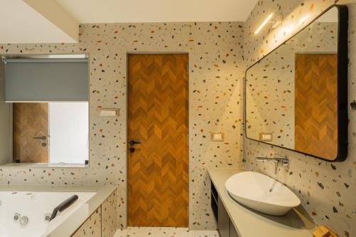 a bathroom with a sink and a tub and a mirror at ELIVAAS Kamerios Maris 1BHK Apartment with Jacuzzi in Goa