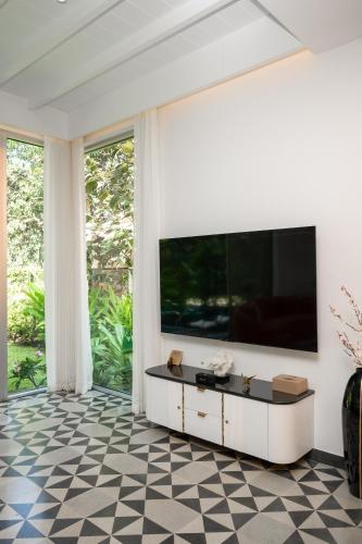 a living room with a large television on a wall at Verona by Vianaar Luxe Garden Pool Villa Assagao in Goa
