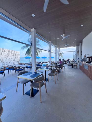 a restaurant with tables and chairs and the ocean at Three Trees Samui Resort - Sarocha Villa in Lamai