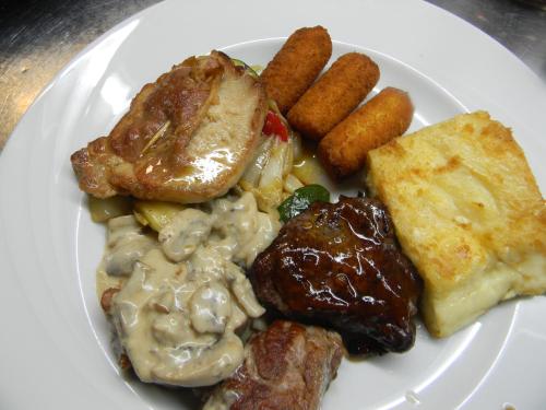 a white plate of food with meat and gravy and potatoes at Hotel Krona Domžale in Domžale