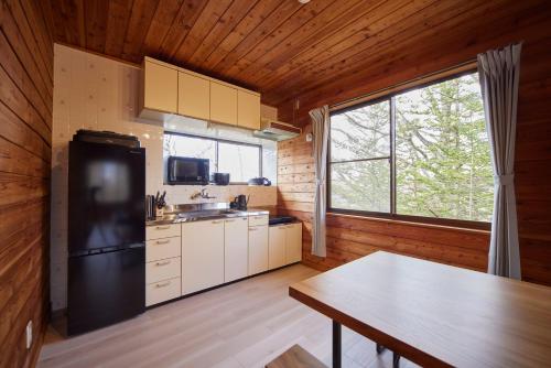 a kitchen with a black refrigerator and a table at rinne 2nd living Kitakaruizawa Forest in Tsumagoi