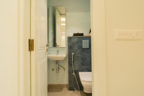 a bathroom with a sink and a toilet and a mirror at ELIVAAS Solace Azure 4 BHK Villa with Pvt Pool in Calangute