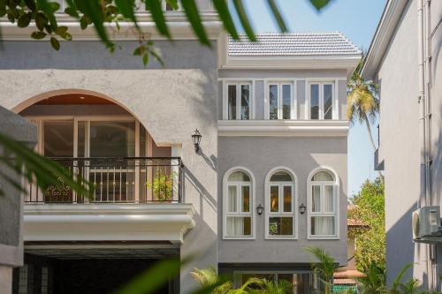 a gray house with a balcony and a porch at ELIVAAS Solace Azure 4 BHK Villa with Pvt Pool in Calangute