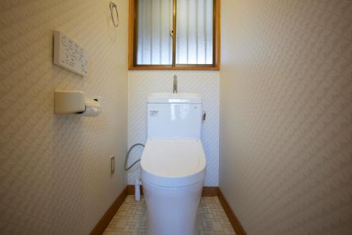 a bathroom with a toilet with a window above it at rinne 2nd living Kitakaruizawa Forest in Tsumagoi