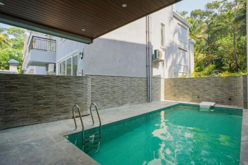 a swimming pool in front of a house at ELIVAAS Solace Azure 4 BHK Villa with Pvt Pool in Calangute