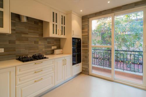 a kitchen with white cabinets and a large window at ELIVAAS Solace Azure 4 BHK Villa with Pvt Pool in Calangute