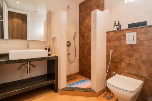 a bathroom with a toilet and a sink and a shower at ELIVAAS Solace Azure 4 BHK Villa with Pvt Pool in Calangute
