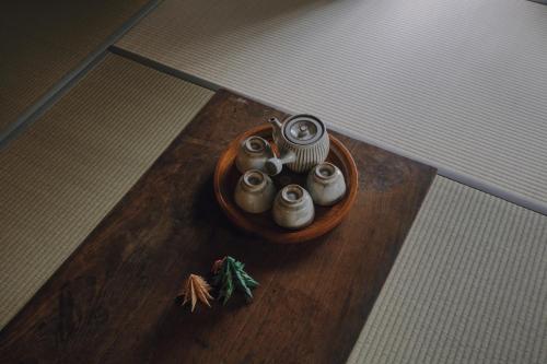 a wooden table with a bowl with four candles on it at 旧雨今雨 in Onomichi