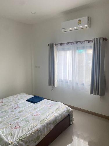 a bedroom with a bed and a window with a air conditioner at Mali Villa in Ban Suan