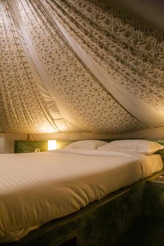 ein Schlafzimmer mit einem Bett mit weißem Himmelbett in der Unterkunft Virama Gokarna in Gokarna