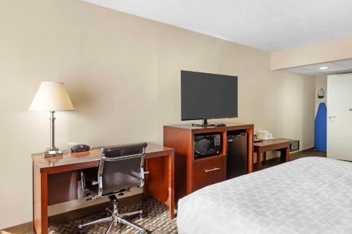 a hotel room with a bed and a desk with a television at Clarion Pointe Research Triangle Park Durham in Durham