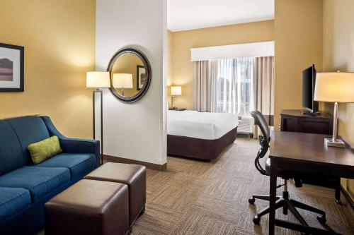 a hotel room with a bed and a couch and a desk at Comfort Suites Frisco in Frisco