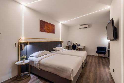 a hotel room with two beds and a tv at Regatta at Kozi Square Kuching in Kuching