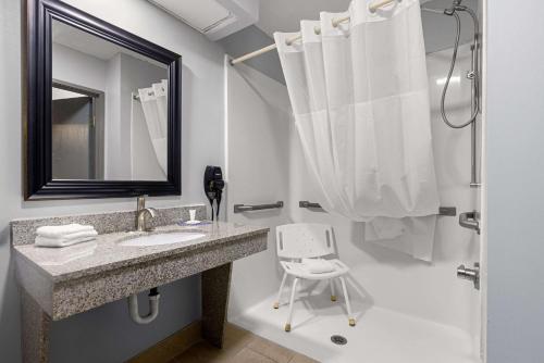 a bathroom with a sink and a mirror and a chair at Clarion Pointe Hinesville near Fort Stewart in Hinesville