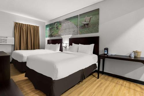 a hotel room with two beds with white sheets at Clarion Pointe Hinesville near Fort Stewart in Hinesville