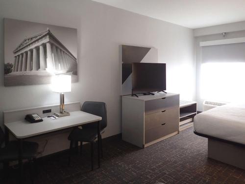 a hotel room with a bed and a desk with a computer at Brentwood Suites Nashville, an Ascend Collection Hotel in Brentwood