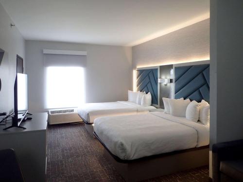 a hotel room with two beds and a flat screen tv at Brentwood Suites Nashville, an Ascend Collection Hotel in Brentwood