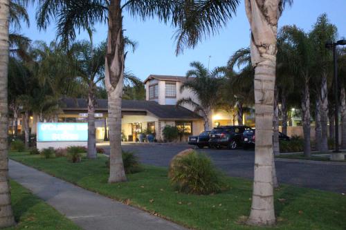 a car parked in front of a house with palm trees at O'Cairns Inn and Suites in Lompoc