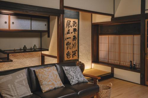 a living room with a black leather couch and wooden shelves at 旧雨今雨 in Onomichi
