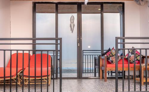 a room with red chairs and a bed and glass doors at Simrose in Agonda