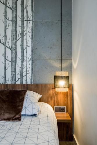 a bedroom with a bed and a night stand with a lamp at Kairos Apartments - Spodek - 100 m od Spodka in Katowice